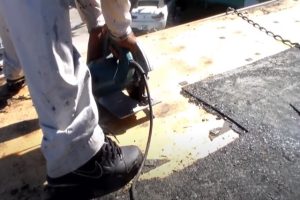 Worker cutting off plywood on commercial flat roof